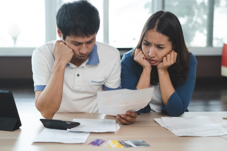 Couple looking glumly at bills worried they are unable to pay moneylenders in Singapore